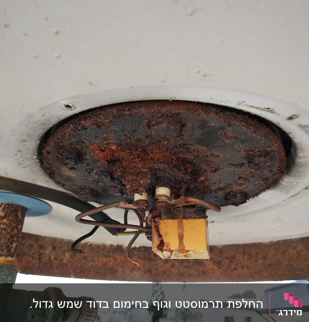 חלק תחתון של דוד שמש עם חלודה וחוטים חשמליים